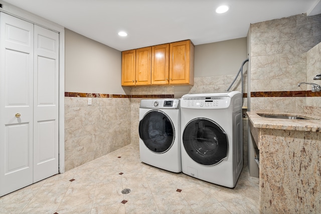 washroom featuring tile walls, separate washer and dryer, sink, and cabinets