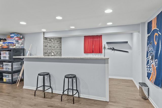 kitchen with a breakfast bar area, sink, and light wood-type flooring