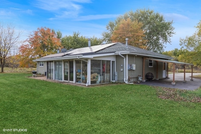 rear view of house featuring a yard, a carport, and a sunroom