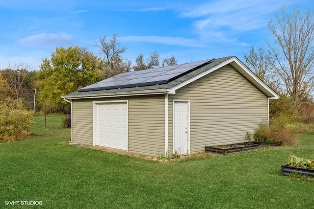 garage featuring solar panels and a yard