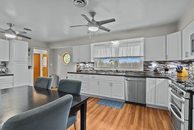 kitchen featuring decorative backsplash, light hardwood / wood-style flooring, white cabinets, and stainless steel appliances