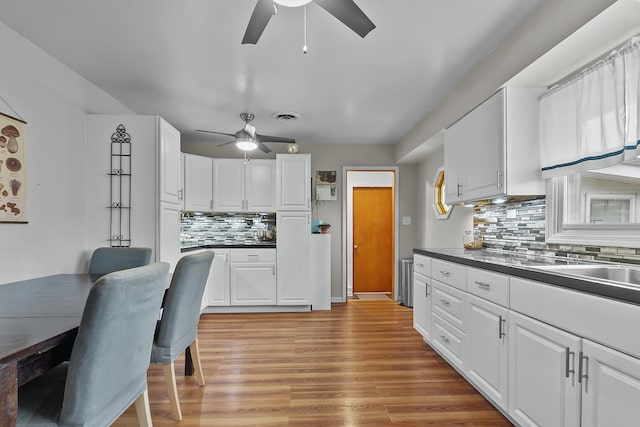 kitchen with tasteful backsplash, white cabinetry, ceiling fan, and light wood-type flooring