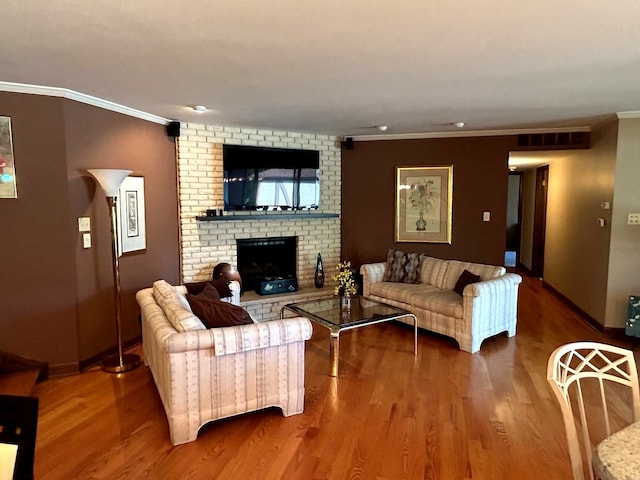 living room with ornamental molding, a brick fireplace, and wood-type flooring