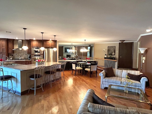 living room with a notable chandelier, hardwood / wood-style flooring, crown molding, and sink