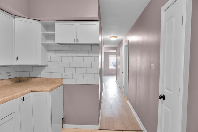 kitchen with white cabinetry, light hardwood / wood-style flooring, and tasteful backsplash