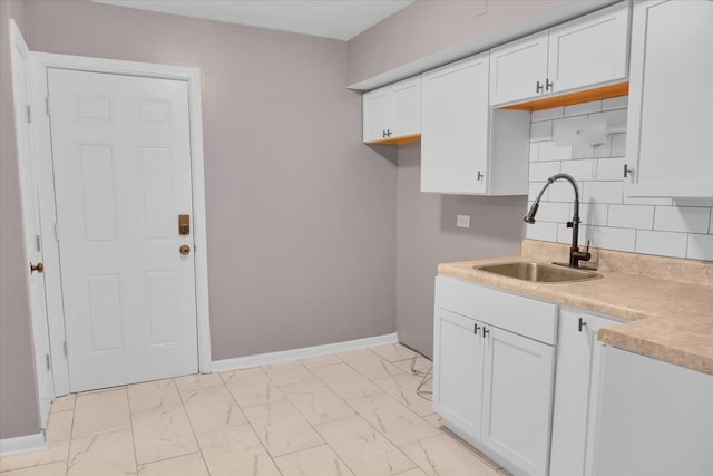 kitchen with white cabinets, backsplash, and sink