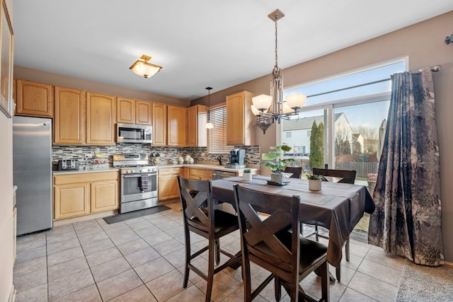 kitchen with decorative light fixtures, a healthy amount of sunlight, stainless steel appliances, and tasteful backsplash