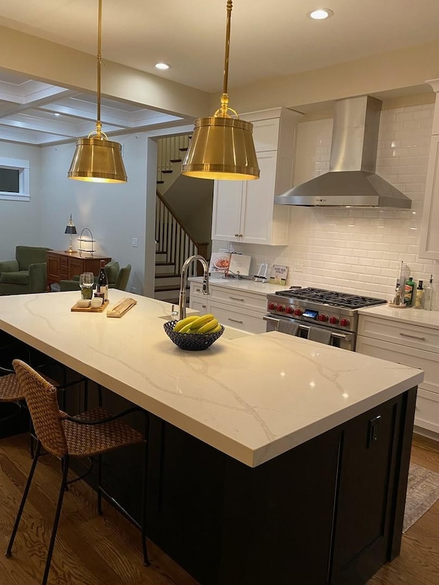 kitchen with high end range, white cabinets, pendant lighting, and wall chimney exhaust hood