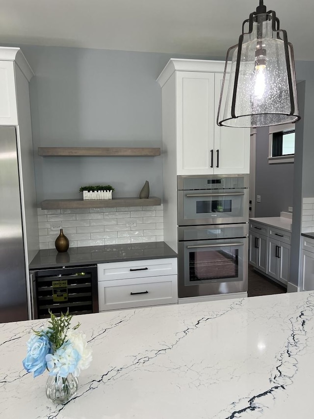 kitchen with wine cooler, light stone counters, stainless steel appliances, and white cabinets