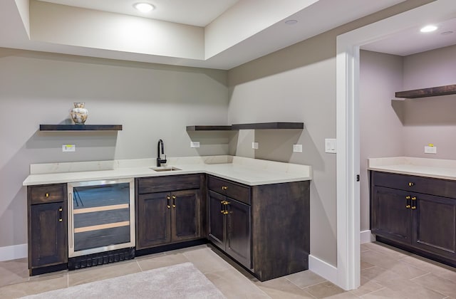 bar featuring wine cooler, sink, light tile patterned floors, and dark brown cabinetry