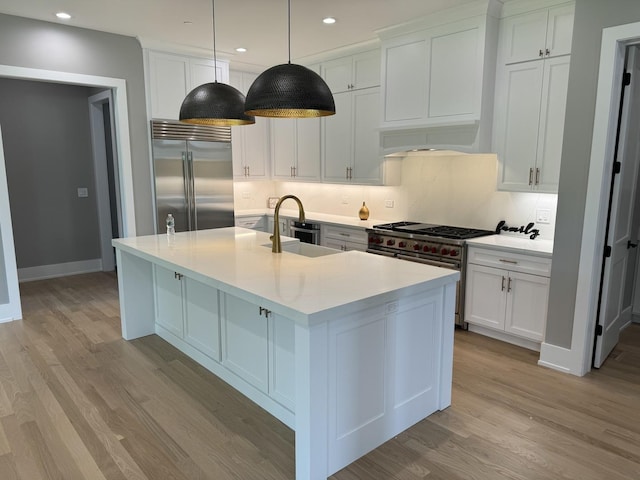 kitchen with hanging light fixtures, high end appliances, sink, and white cabinets