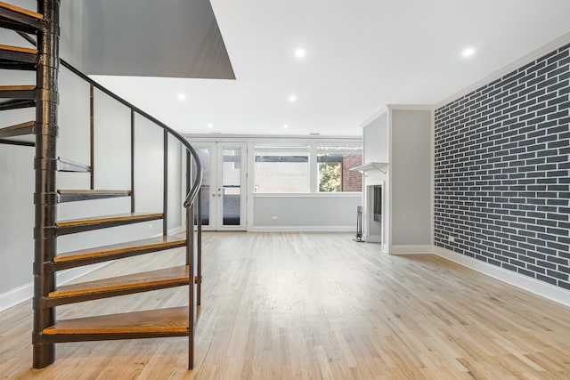 stairs with wood-type flooring, crown molding, and brick wall