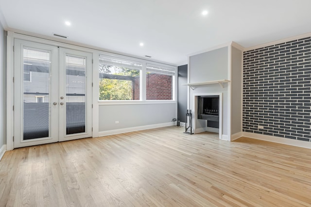 unfurnished living room with french doors, light wood-type flooring, and brick wall