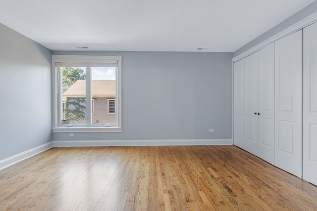 unfurnished bedroom with light hardwood / wood-style flooring and a closet