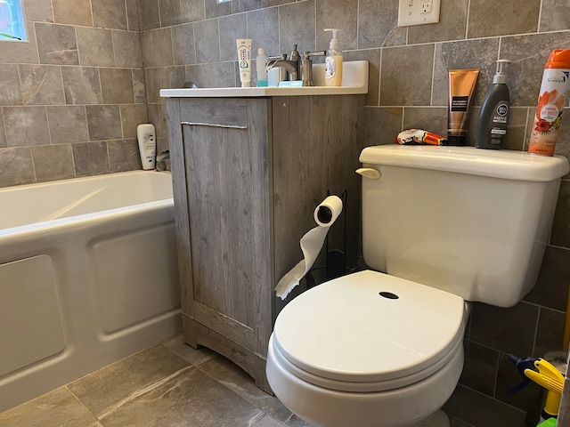 bathroom featuring vanity, tile walls, toilet, and a tub