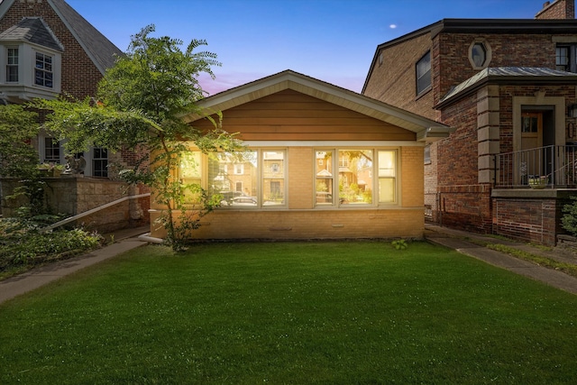 back house at dusk featuring a yard