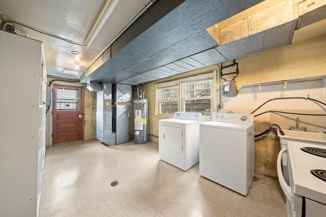 clothes washing area with washer and clothes dryer, gas water heater, sink, and heating unit