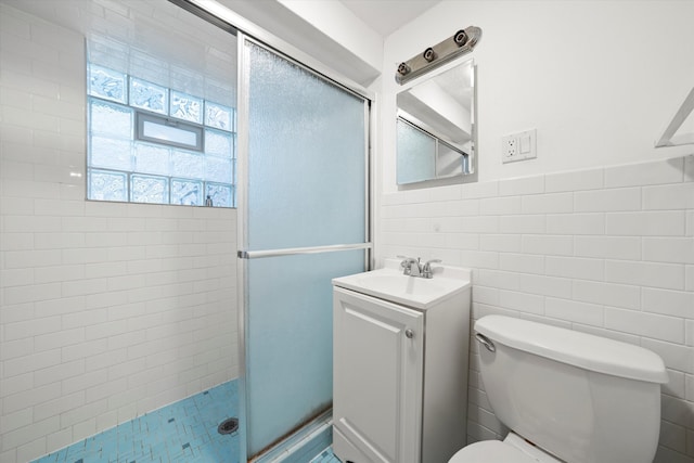 bathroom featuring tile walls, vanity, toilet, and a shower with door