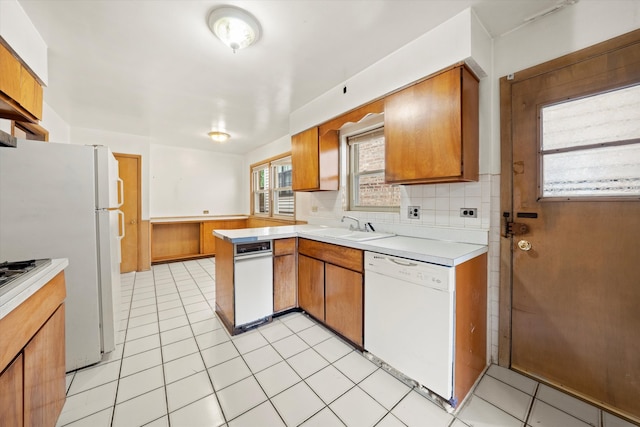 kitchen featuring sink, kitchen peninsula, decorative backsplash, white appliances, and light tile patterned floors