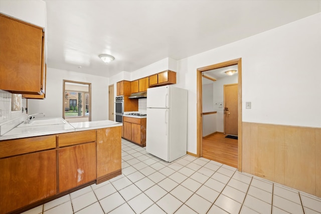 kitchen with light tile patterned flooring, kitchen peninsula, sink, and white appliances