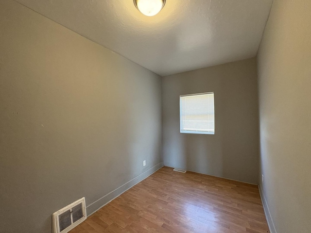 unfurnished room with light wood finished floors, baseboards, and visible vents