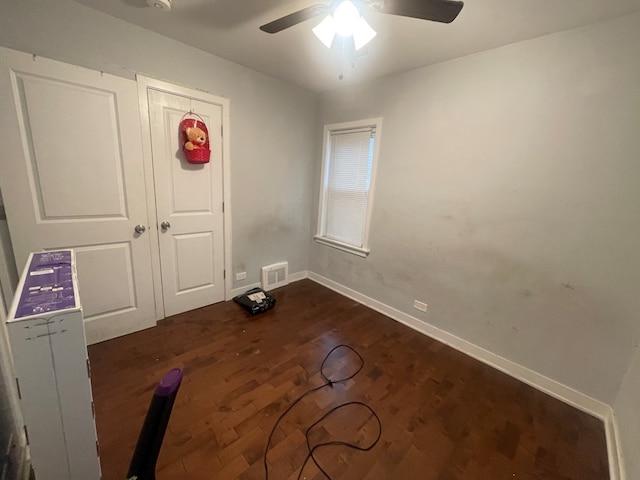 unfurnished bedroom with ceiling fan, a closet, and dark hardwood / wood-style floors