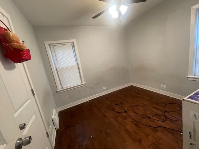 spare room with dark wood-type flooring, vaulted ceiling, and ceiling fan