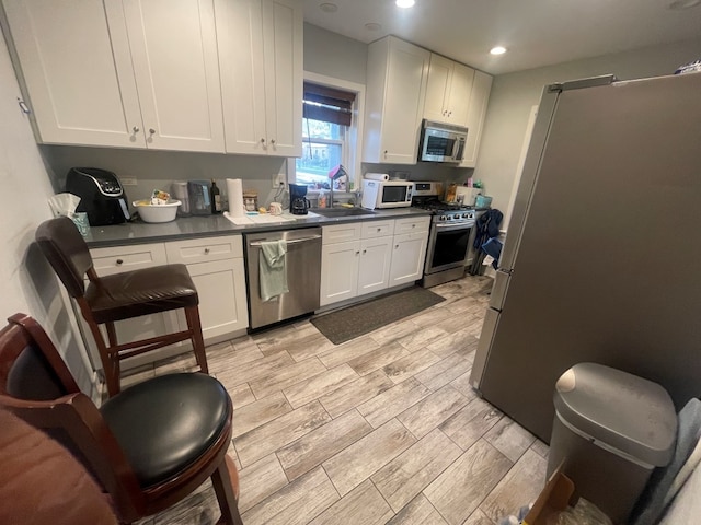 kitchen with sink, white cabinets, stainless steel appliances, and light hardwood / wood-style flooring