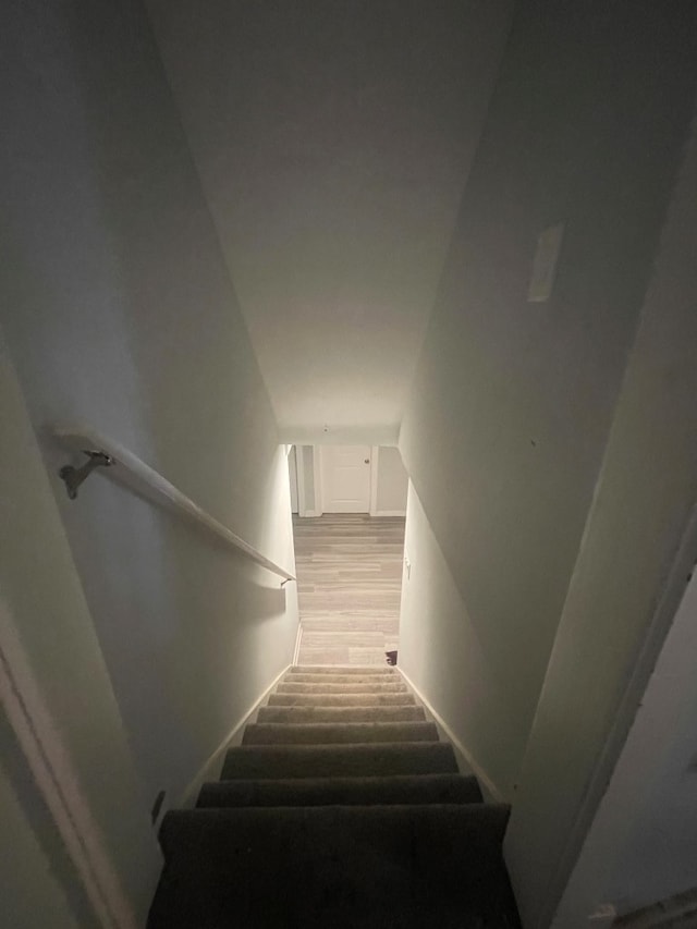 stairs with wood-type flooring and vaulted ceiling