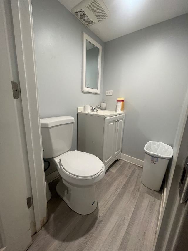 bathroom with hardwood / wood-style flooring, toilet, and vanity