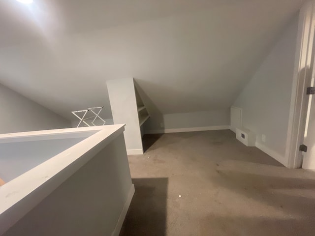 bonus room with vaulted ceiling and light colored carpet