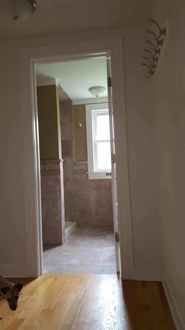 hallway with tile walls and hardwood / wood-style flooring