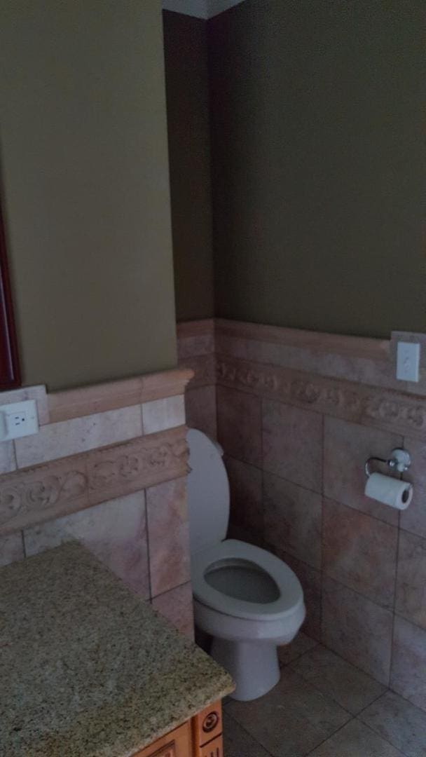 202 S Birch St, Wenona, IL 61377 - bathroom with tile walls, toilet, tile patterned flooring, and a wainscoted wall