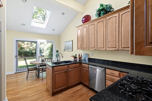 kitchen featuring light hardwood / wood-style flooring, vaulted ceiling with skylight, kitchen peninsula, and sink