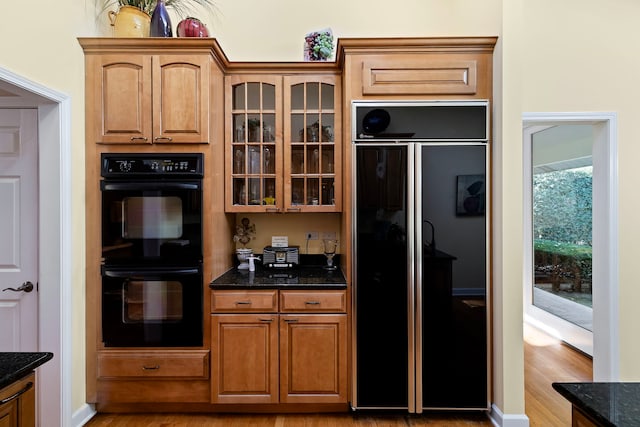 kitchen featuring dark stone countertops, black appliances, and light hardwood / wood-style floors