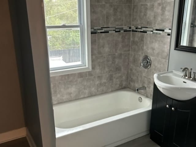 bathroom featuring tiled shower / bath combo and vanity