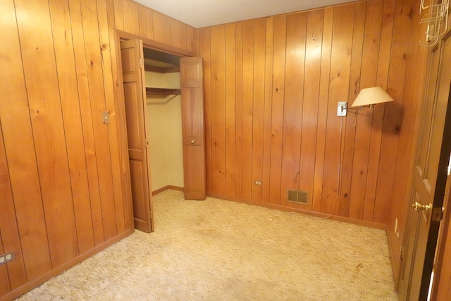 unfurnished bedroom with wood walls, light colored carpet, and a closet