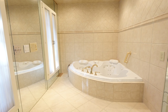 bathroom with tile walls, tiled bath, and tile patterned floors