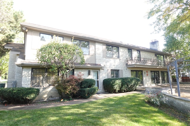 view of property featuring a balcony and a front yard