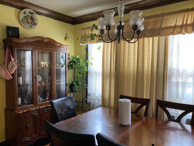 dining space with a notable chandelier, ornamental molding, a textured ceiling, and a healthy amount of sunlight