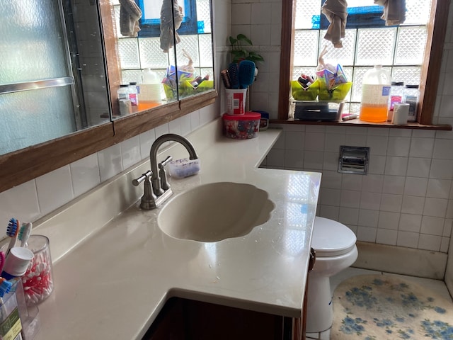 bathroom featuring vanity, tile walls, toilet, and tasteful backsplash