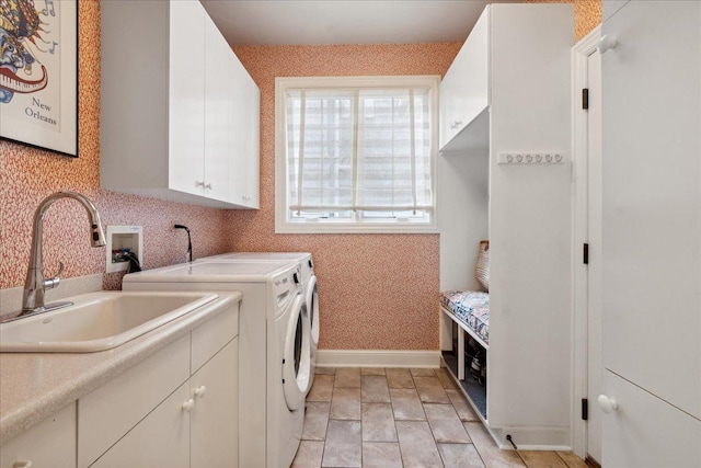 clothes washing area with cabinets, washer and clothes dryer, and sink