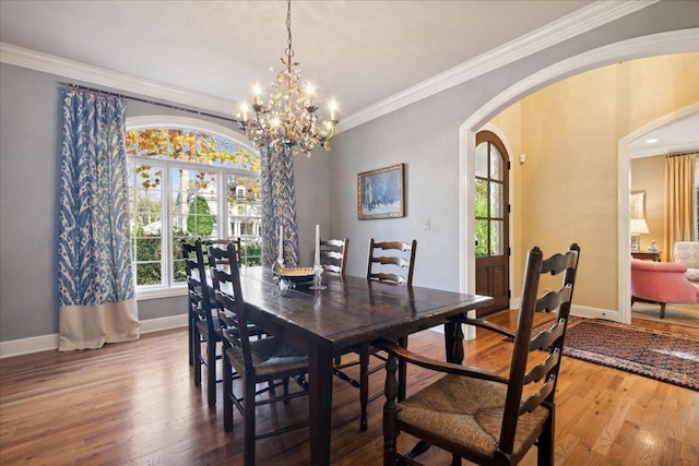 dining area with crown molding, wood-type flooring, and an inviting chandelier