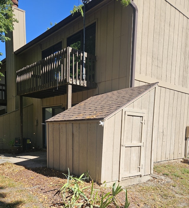 view of side of home featuring a storage unit and a wooden deck