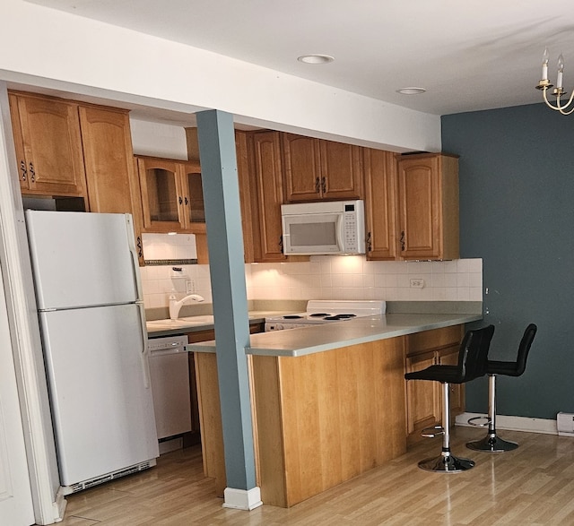 kitchen featuring white appliances, light hardwood / wood-style flooring, decorative backsplash, and kitchen peninsula