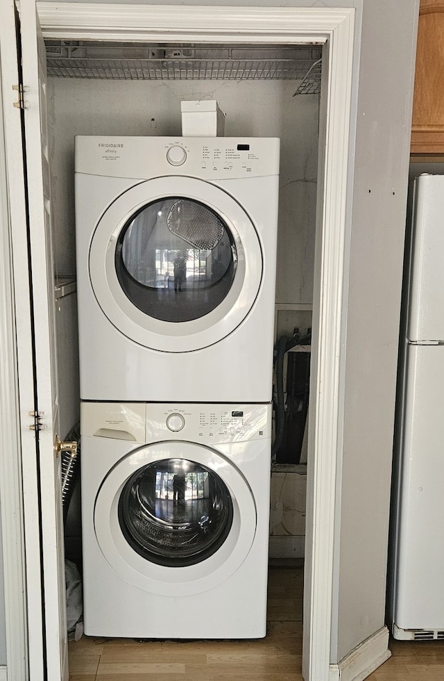 clothes washing area with light hardwood / wood-style floors and stacked washer and clothes dryer