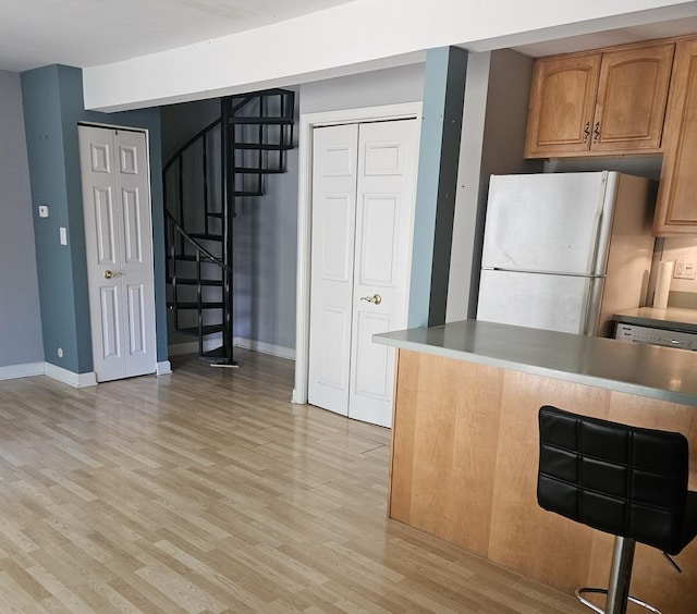 11 Saint Thomas Colony Unit 4, Fox Lake, IL 60020 - kitchen featuring freestanding refrigerator, light wood-style floors, baseboards, and a breakfast bar area