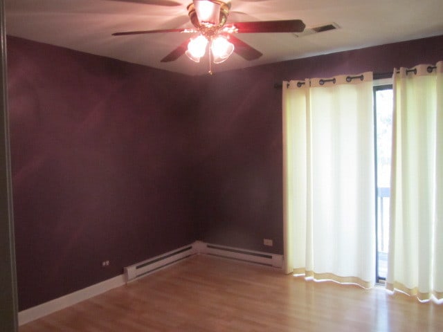 spare room featuring hardwood / wood-style flooring, a baseboard heating unit, and ceiling fan