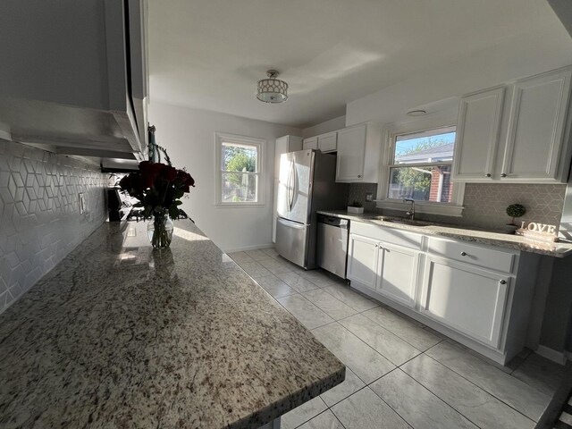 kitchen with light stone countertops, appliances with stainless steel finishes, sink, and white cabinetry