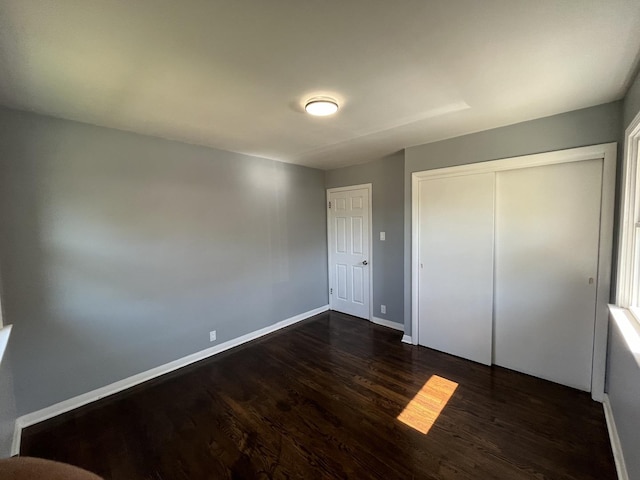 unfurnished bedroom with dark hardwood / wood-style flooring and a closet